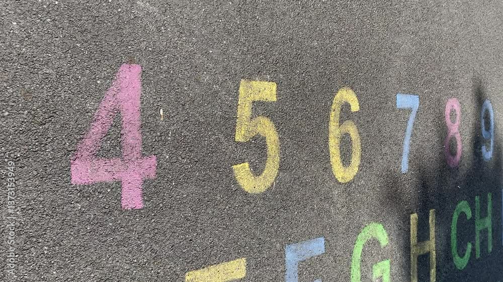 alphabet and numbers are drawn with color paint on a children's asphalt playground to learn and play. the alphabet educational element learning space.
