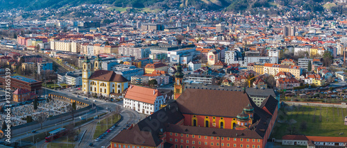 Obraz na płótnie Aerial view of Innsbruck, Austria, featuring Wilten Basilica with twin yellow towers, a cemetery, historic buildings, and the Nordkette mountain range. w salonie