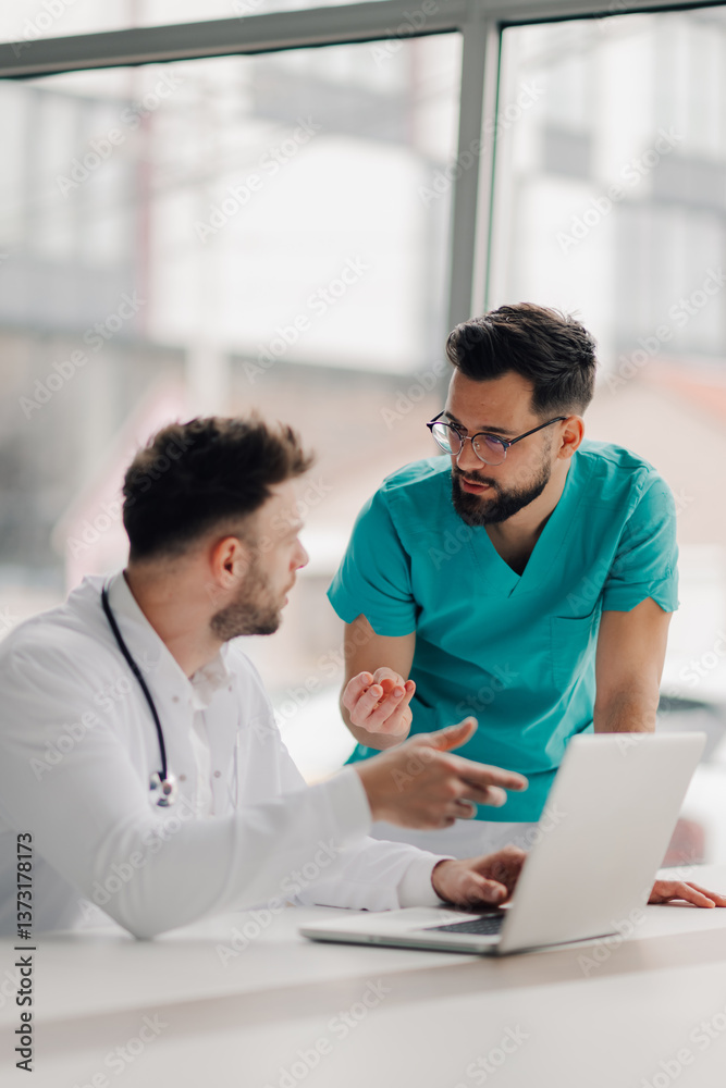Doctors discussing patient data using laptop in hospital room Doctors discussing patient data using laptop in hospital room