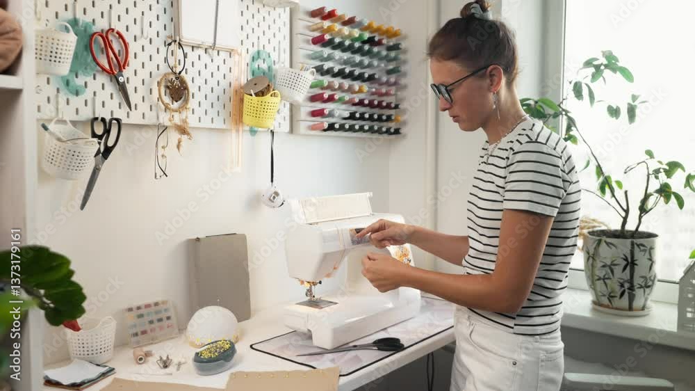 Female designer working on new clothing collection at home, adjusting sewing machine. Passionate entrepreneur creating handmade fashion. Concept of independent business and creative industry. Female designer working on new clothing collection at home, adjusting sewing machine. Passionate entrepreneur creating handmade fashion. Concept of independent business and creative industry.