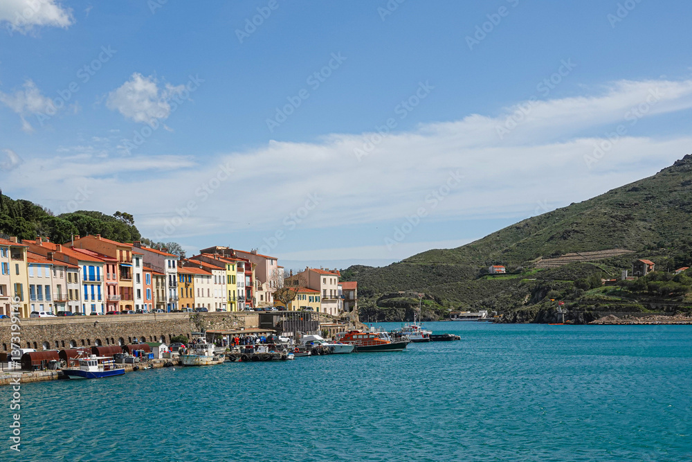 Charming buildings line the harbor as fishing boats bob gently in the calm waters. Port-Vendres, Occitanie, France
