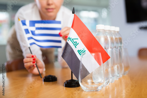 Photos Employee of delegation prepares negotiating table - sets up the flag of Greece a