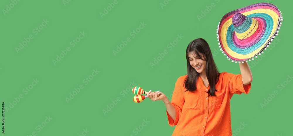 Fototapeta premium Young woman with sombrero and maracas on green background with space for text