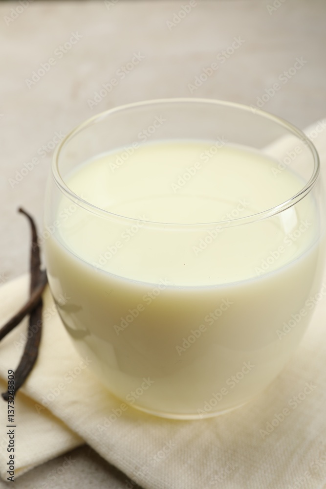 Glass of milk and vanilla pods on light grey table, closeup Glass of milk and vanilla pods on light grey table, closeup