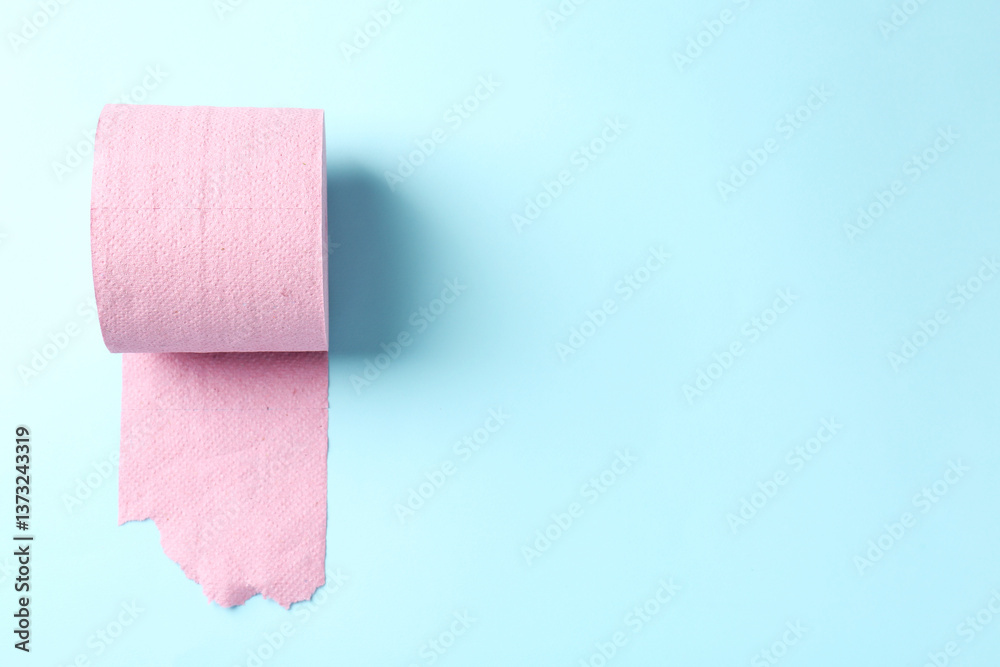 Obraz premium Pink toilet paper roll on light blue background, top view. Space for text
