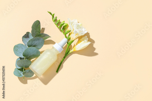 Bottle of essential oil, eucalyptus branch and freesia flower on color background