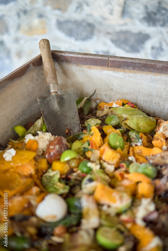 Close-up of compost bin with food scraps and gardening trowel