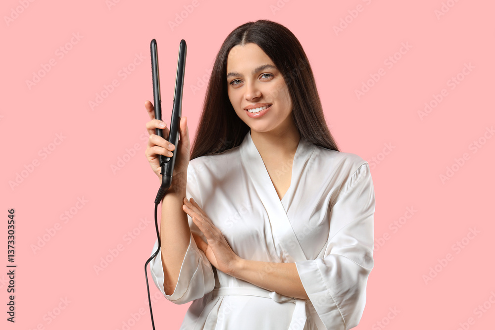 Pretty young woman in bathrobe with hair straightener on pink background Pretty young woman in bathrobe with hair straightener on pink background