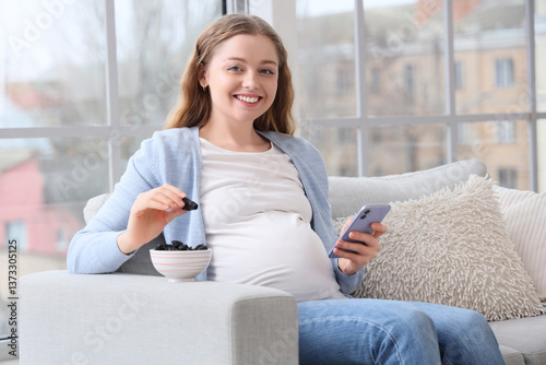 Free Download Young pregnant woman with dried prunes and mobile phone sitting on sofa at home - GFXLoad