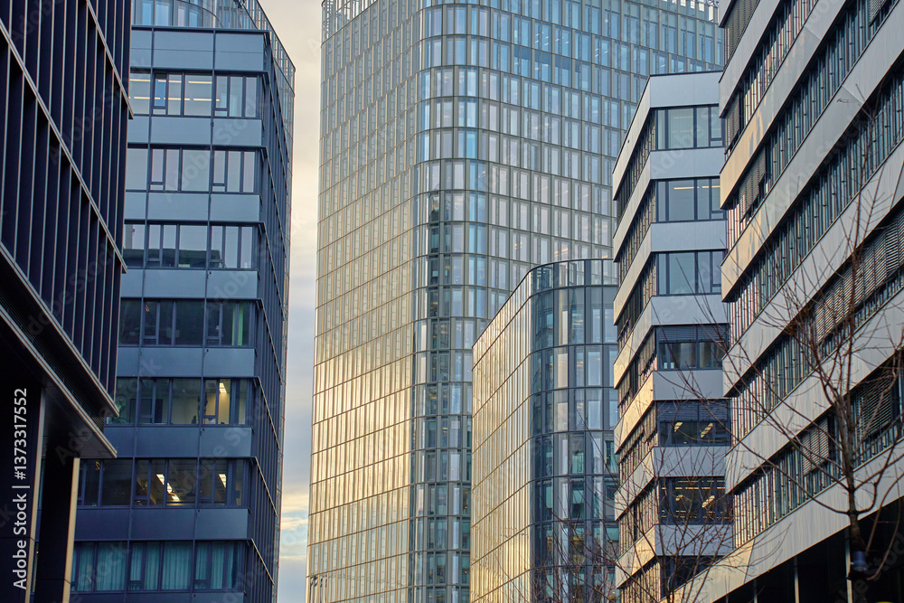 Fototapeta premium Modern glass skyscrapers reflecting blue sky and surrounding city. High-rise office buildings with curved glass facades. Contemporary architecture in city business district