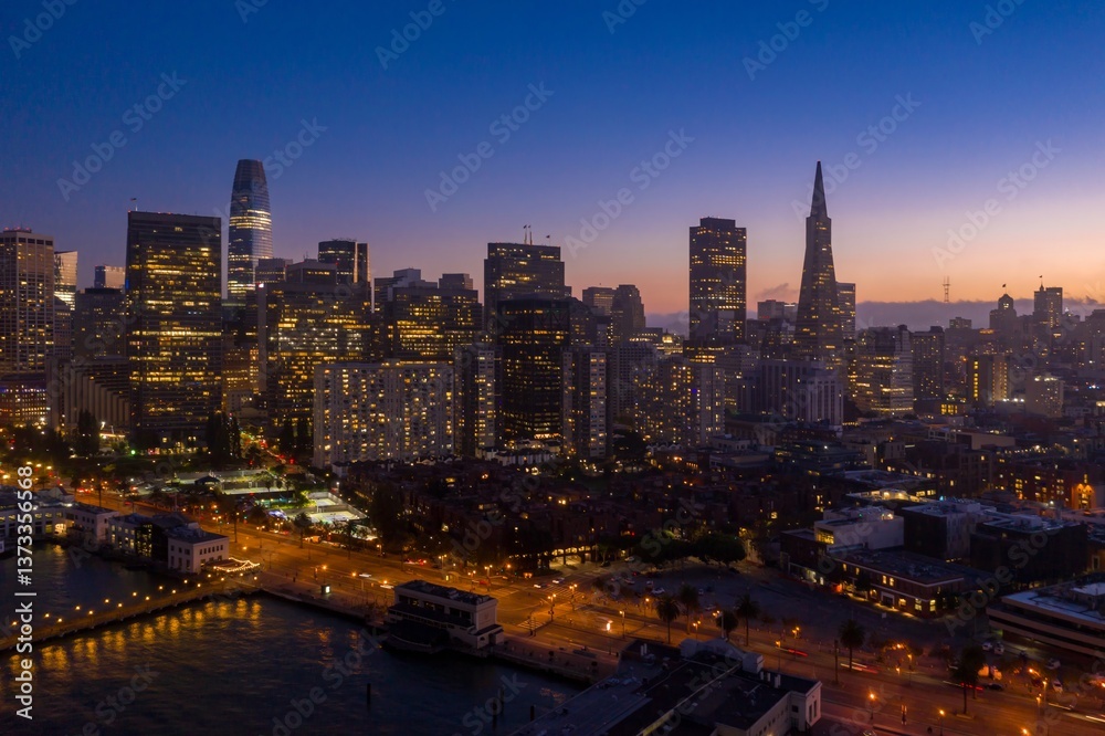 Obraz premium Aerial view of the San Francisco skyline at dusk in California, USA. The city lights illuminate the buildings and streets below. The photo captures the beauty of the city.