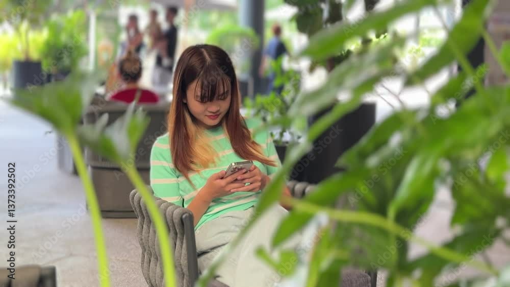 An East Asian woman using a smartphone at the park during the daytime. An East Asian woman using a smartphone at the park during the daytime.