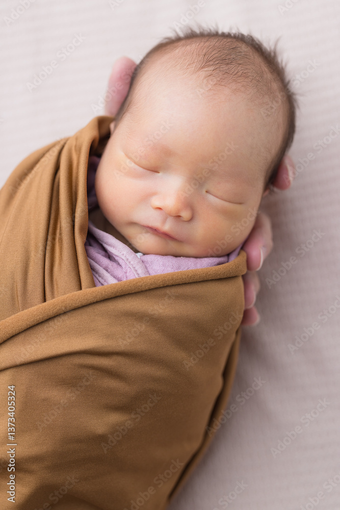 Tiny newborn wrapped in soft brown fabric
