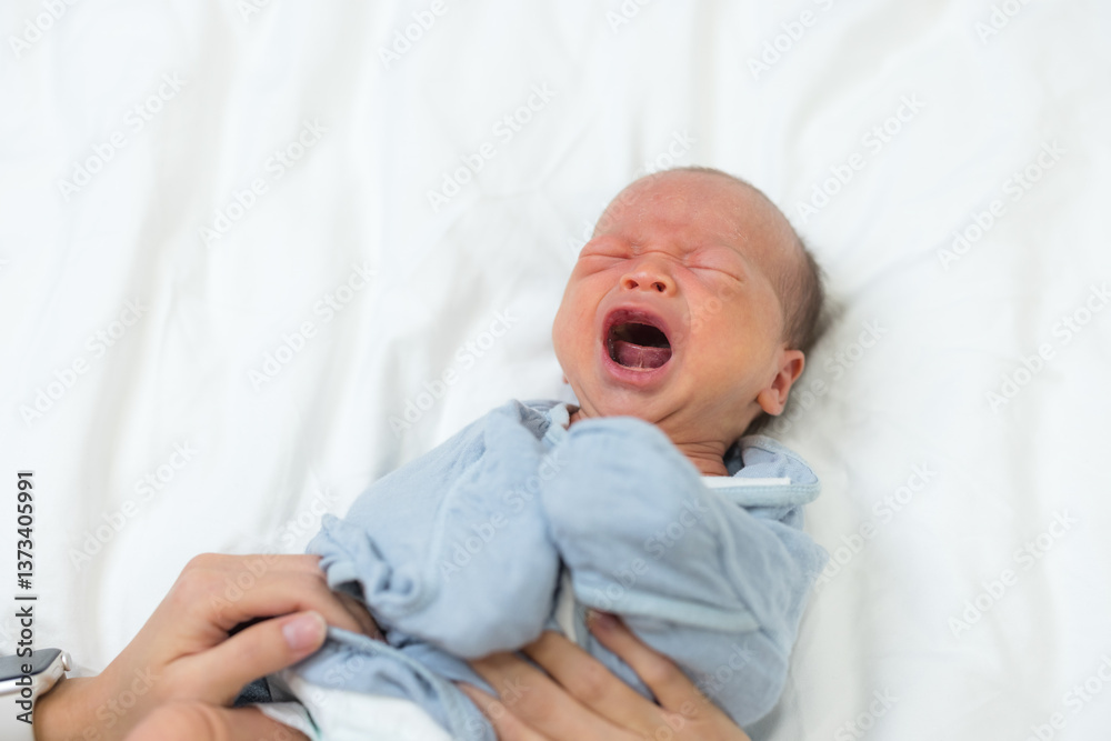 Mom cuddling little baby on soft white bed
