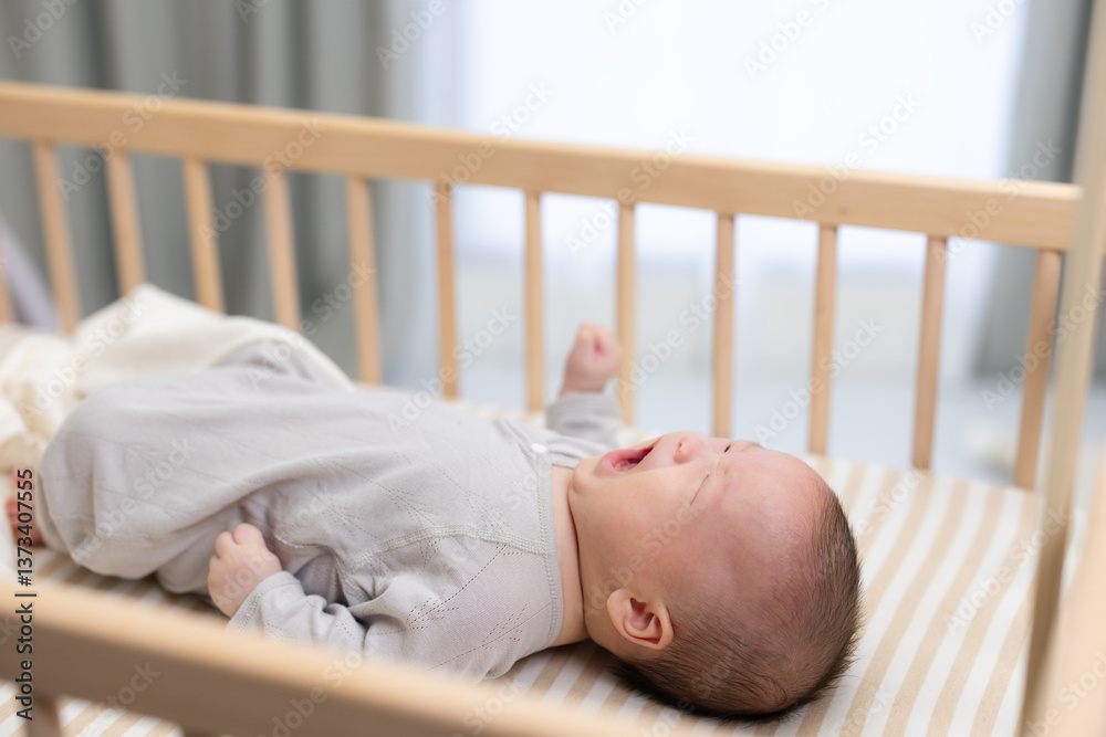 Crying baby lying in wooden crib at home