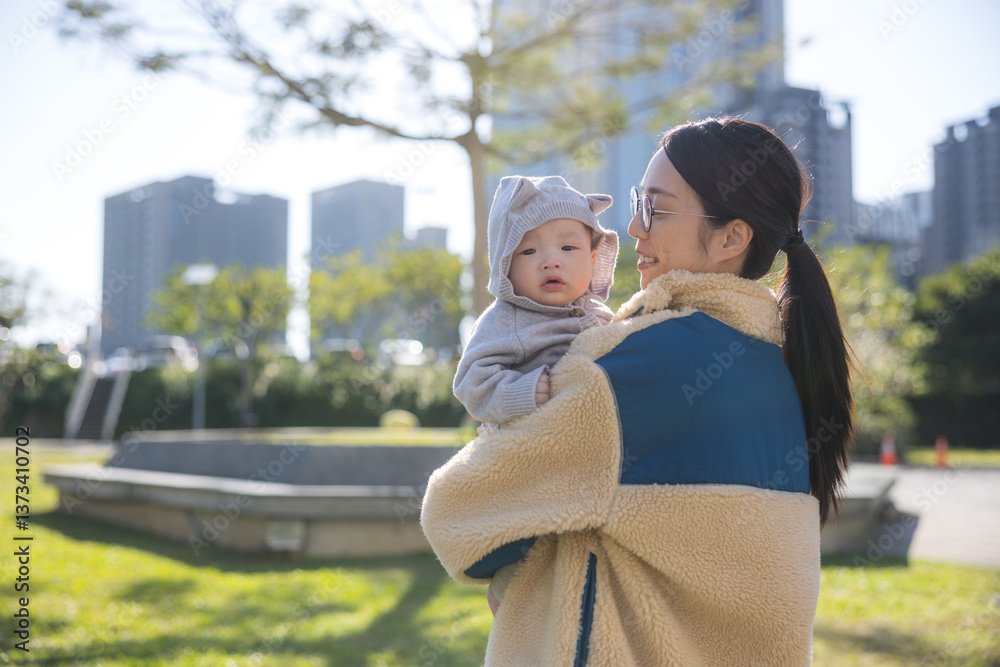 Mother holding baby in sunny outdoor park