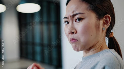 Woman reacts to unpleasant smell with displeasure and confusion in indoor setting