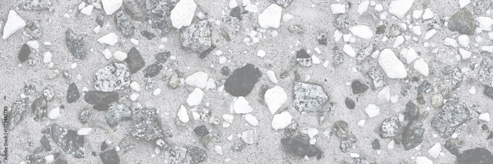 Concrete wall texture with pebbles. Decorative rough concrete surface with white, black and gray stones. Wide panoramic texture for background and design.