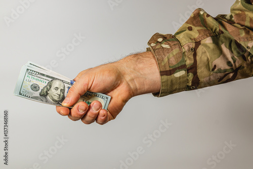 Hand holding cash with military camouflage sleeve visible