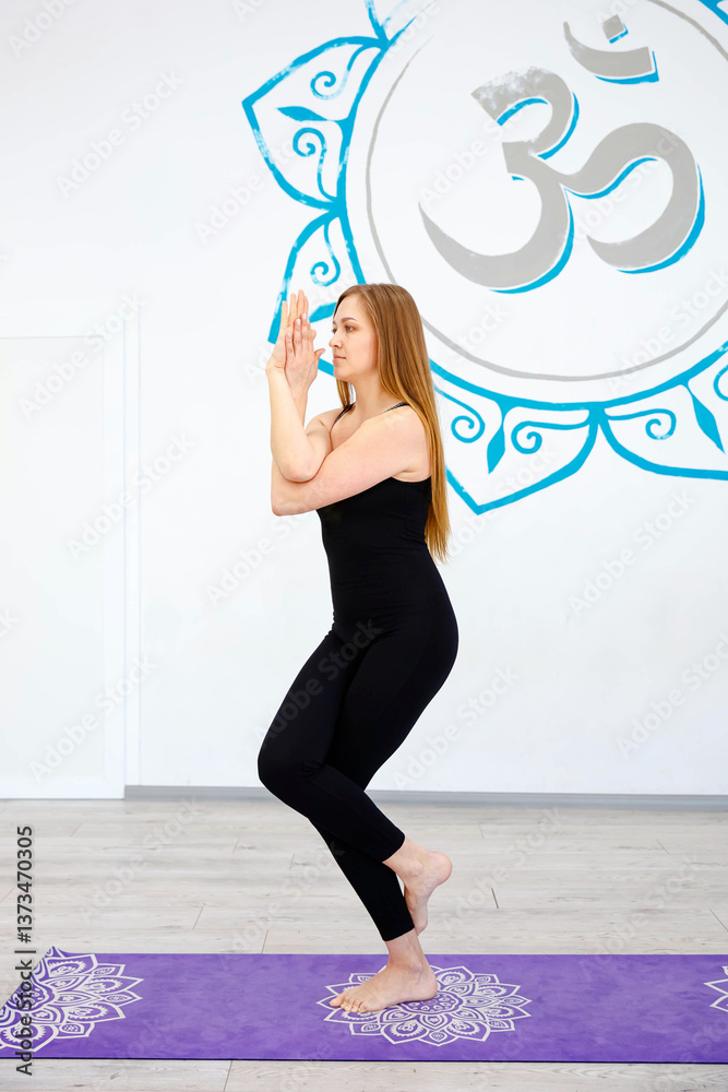 Woman practicing eagle pose (Garudasana) in a yoga studio
