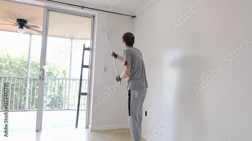 Men painting a wall use paint roller on extension pole white wall coloring painting