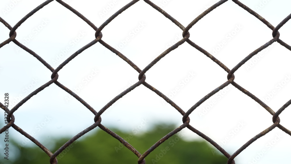 Rusty mesh fencing with blurred tree in the background. Rusty mesh fencing with blurred tree in the background.