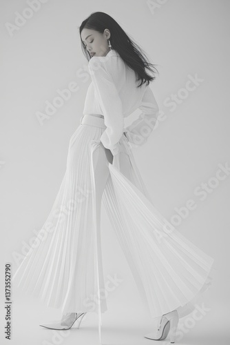 Ethereal woman in a layered, flowing dress. Back view, monochrome elegance with a subtle reflection. A study in graceful form and light