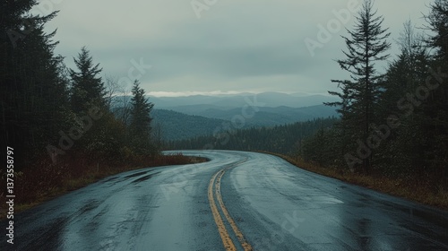 A cinematic shot of a winding mountain road on a rainy afternoon, taken from a high vantage point. The wet asphalt reflects the moody gray sky.