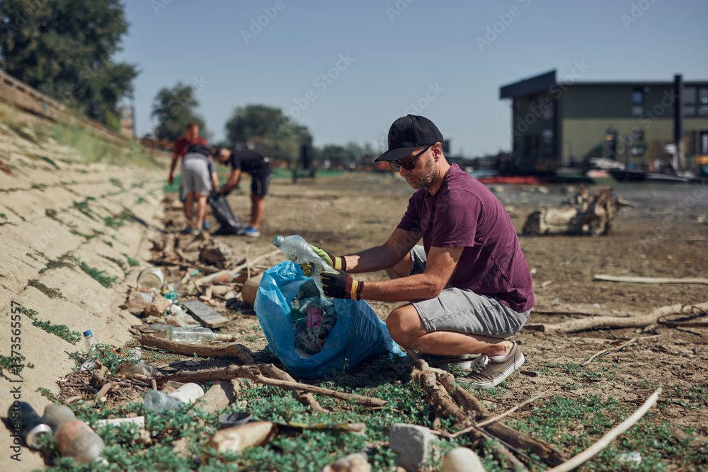 Environmental activist cleaning river shore from piled up trash.