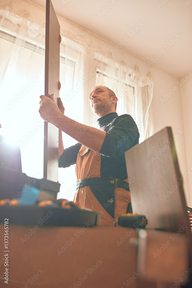 Carpenter working and assembling furniture in a new apartment.
