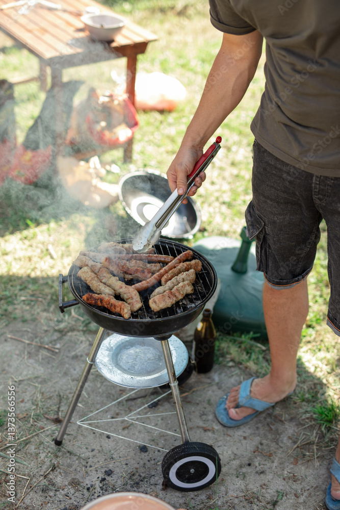 Man preparing barbeque in the garden on a hot summer day.