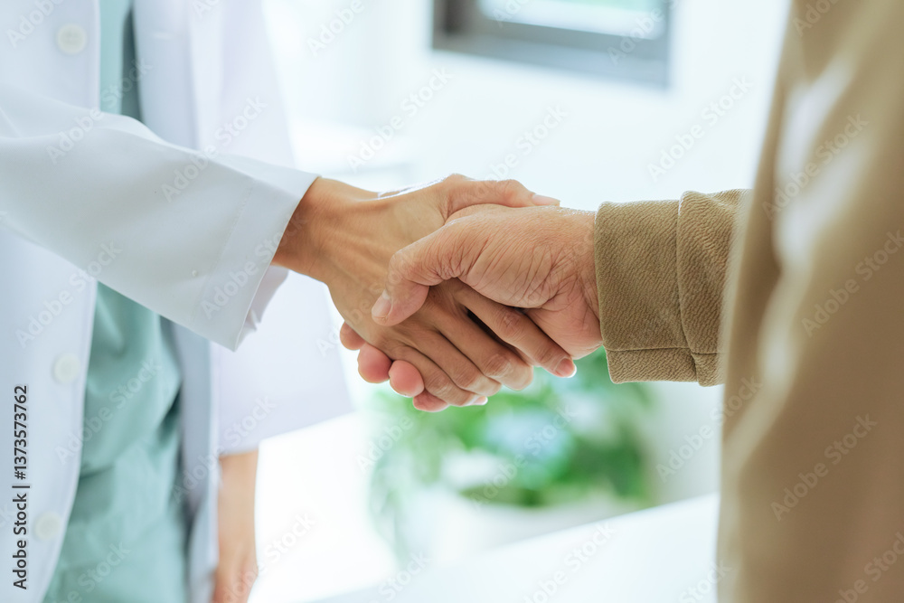 close-up shot of a doctor and an elderly patient shaking hands during a visit at the hospital.
