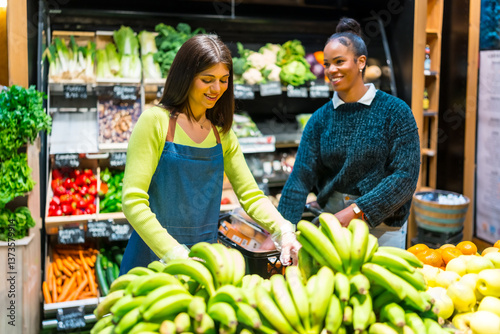 Supermarket employees arranging fresh bananas in produce section