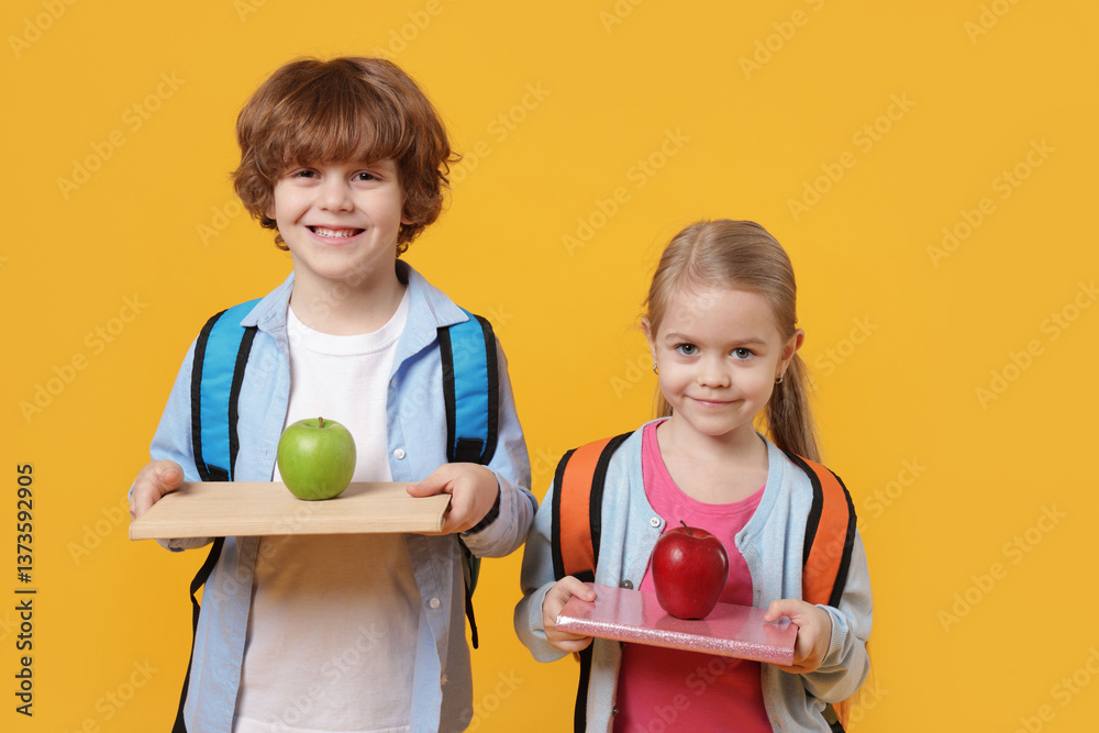 School children with books and apples on orange background