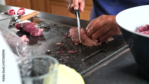 A person is cutting meat on a cutting board