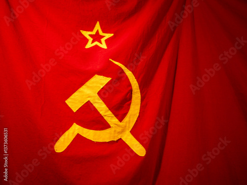 Close-up of the Soviet Union flag featuring yellow hammer and sickle with a star on a red fabric background.