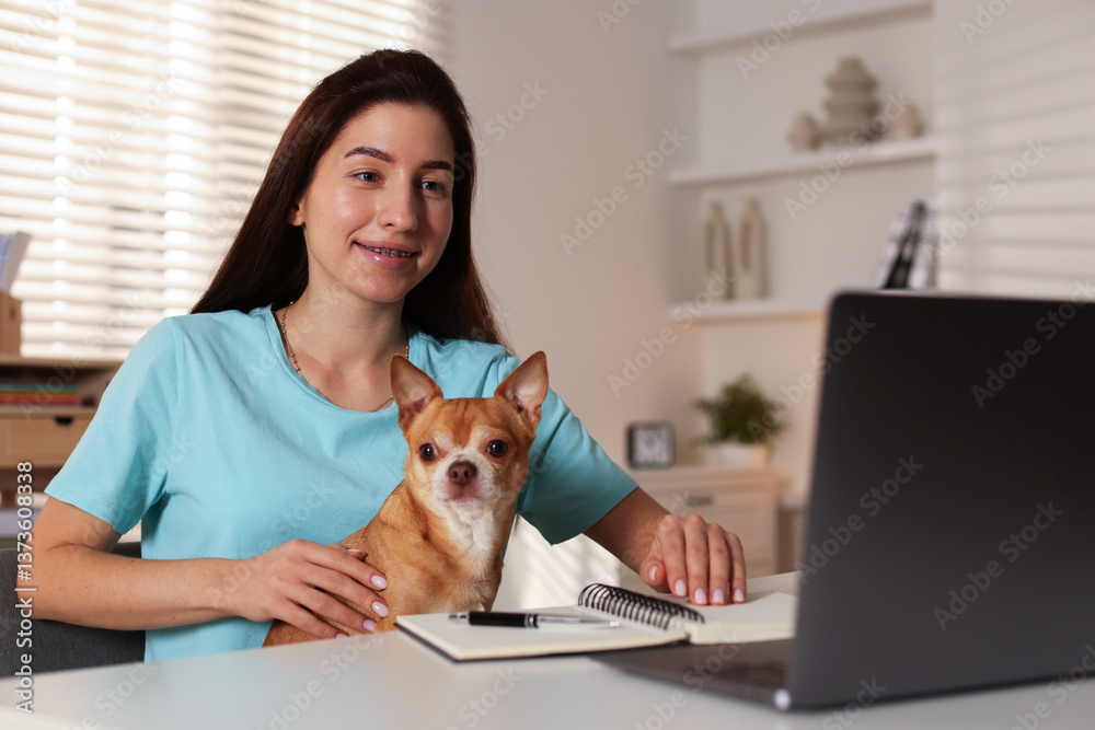 Young woman with her cute dog working on laptop at desk in home office Young woman with her cute dog working on laptop at desk in home office