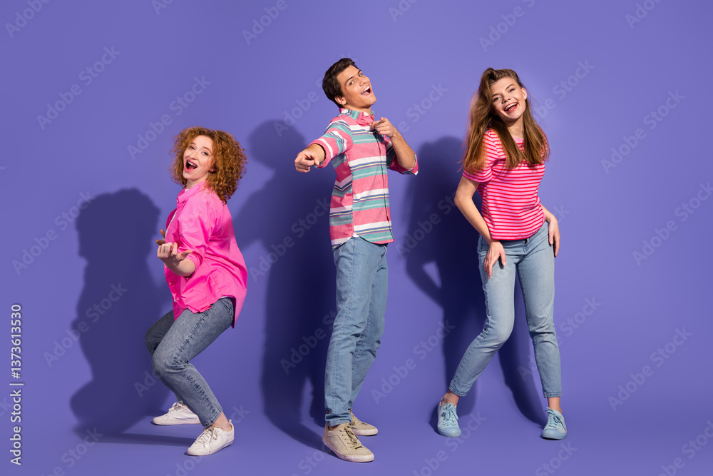Obraz premium Young friends joyfully posing for a fun photoshoot in vibrant casual attire on a colorful purple background with expressive gestures
