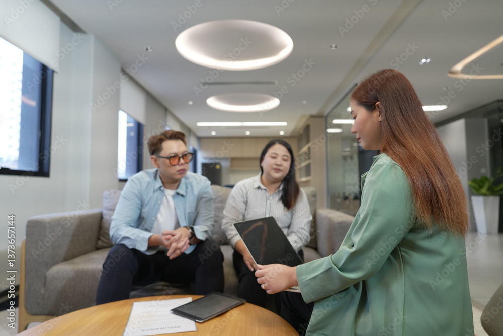 Asian female sales and marketing staff holding laptop explaining insurance presenting life insurance to male and female customers sitting in office company lounge.
