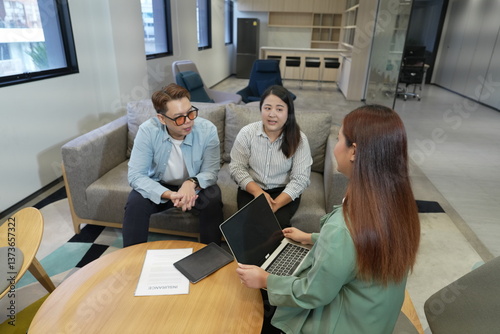 Obraz na płótnie Asian female salesperson presenting business to investors. Asian male and female presenting insurance plans with laptop in office company lounge. w salonie