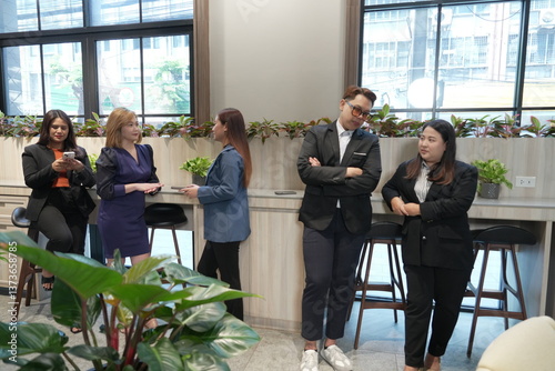Obraz na płótnie A team of Asian male and female employees in business suits take a break and chat with each other in the company lobby. w salonie
