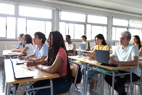 University students taking notes and following lesson in classroom