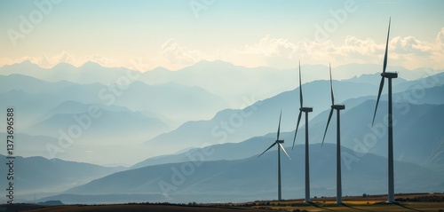 Majestic wind turbines stand silhouetted against a range of distant mountains, hills, rotor, alternative