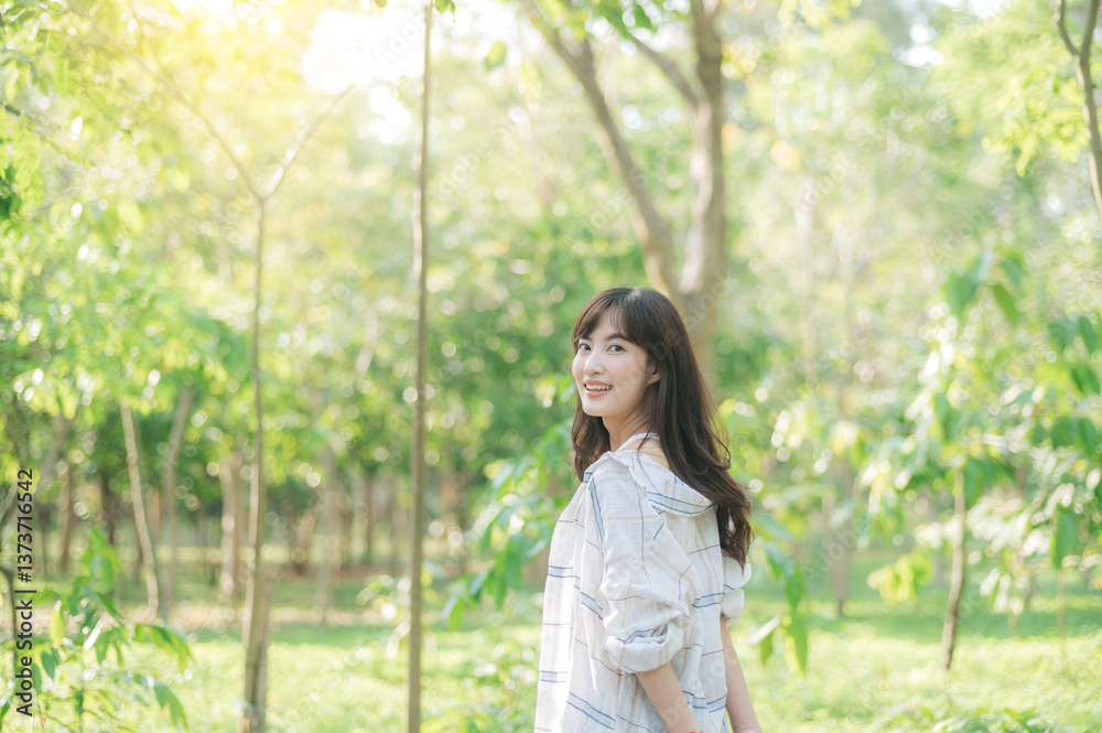 Asian woman enjoying summer outdoors, breathing fresh air in lush green forest with sunlight filtering through trees, feeling relaxed Asian woman enjoying summer outdoors, breathing fresh air in lush green forest with sunlight filtering through trees, feeling relaxed