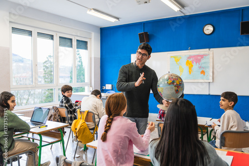 Geography teacher explaining lesson using globe in classroom