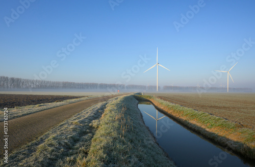 Wind turbines in a frosty countryside landscape in the Netherlands during winter.