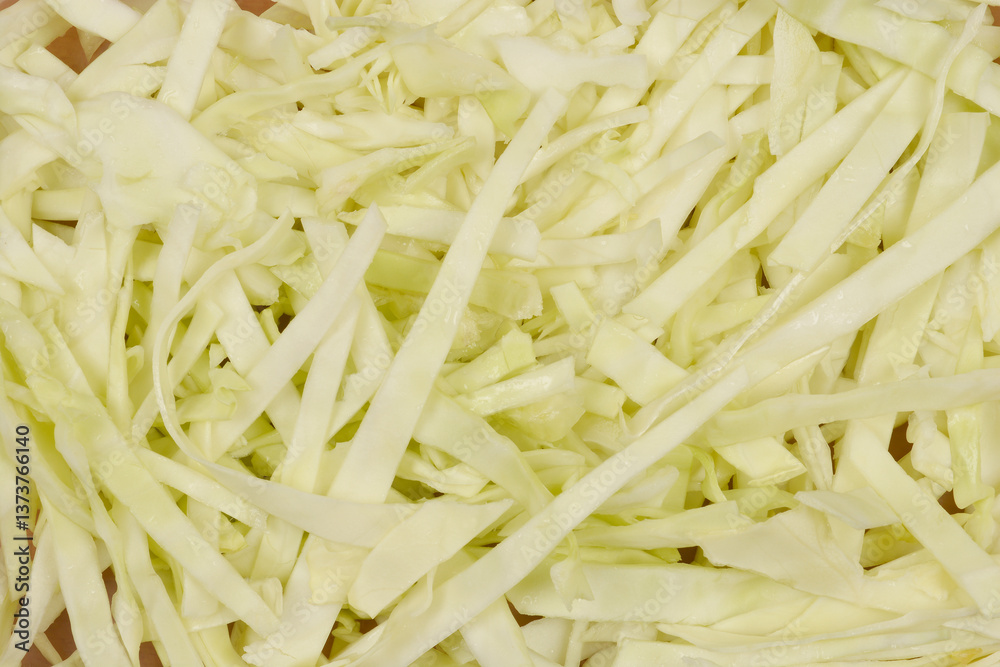 A close-up, top-down view of freshly shredded white cabbage, showcasing its light color and delicate texture A close-up, top-down view of freshly shredded white cabbage, showcasing its light color and delicate texture
