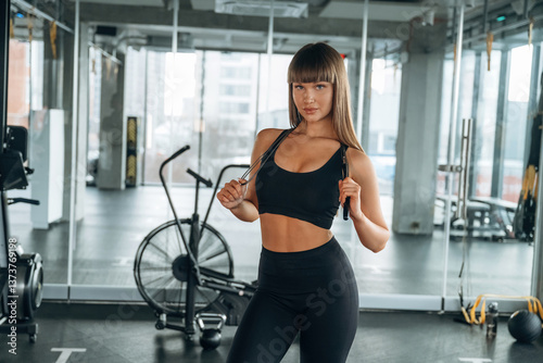 Jumping rope in hands and on the neck. Young woman is in the gym