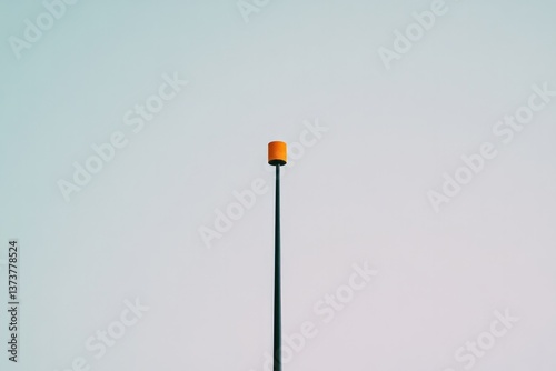 Minimalistic pole topped with bright orange element against pale