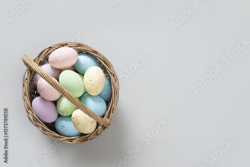 Obraz na płótnie Easter pastel eggs in wicker basket for Happy holiday on gray background. View from above. Greeting card with copy space. w salonie